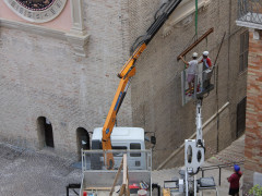 Gli operai a lavoro per riposizionare la seconda lapide con il bollettino della vittoria di Diaz sulla parete ovest della Torre civica di Macerata